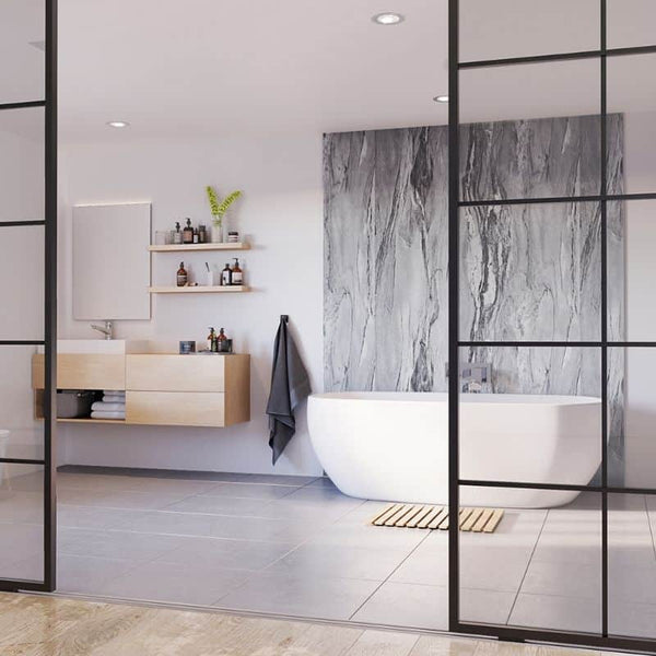 Modern bathroom interior with elegant freestanding bathtub, marble wall design, floating vanity sink, wooden accents, recessed lighting, glass partition, and luxury toiletry items.