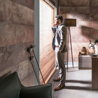 Businessman in modern office interior looking out the window, pensive professional man in suit, stylish workspace with designer furniture, brown and grey color scheme, contemplative mood, urban office life