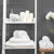 Modern bathroom decor with fluffy white towels, candles, orchids, and soap dispenser on shelves against dark gray textured wall tiles