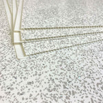 Terrazzo pattern surface with white binder bars or tile leveling spacers on top, construction and flooring concept, close-up view of installation accessories for aligning tiles.