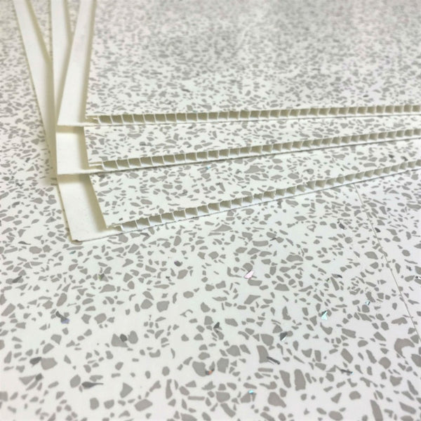 Terrazzo pattern surface with white binder bars or tile leveling spacers on top, construction and flooring concept, close-up view of installation accessories for aligning tiles.