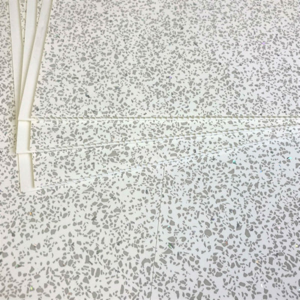 Terrazzo flooring texture with random speckled pattern and white PVC pipes laying on the surface