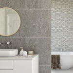 Modern bathroom interior design with marble tiles, freestanding bathtub, round mirror, white vanity cabinet, and stylish sink accessories