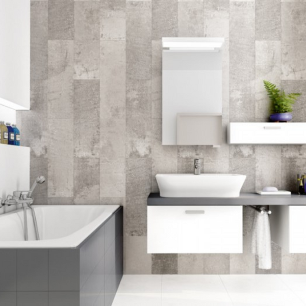 Modern bathroom interior with gray textured tile wall, white sleek bathtub, floating vanity sink, rectangular mirror, and decorative green plant.