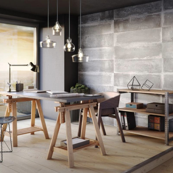 Modern home office interior with industrial design, wooden trestle desk, shelving unit with storage boxes, hanging pendant lights, designer table lamp, minimalist decorations, and large window with natural light.