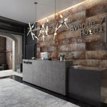 Modern hotel lobby with industrial-chic decor, concrete reception desk, geometric pendant lights, exposed brick and rustic stone wall with hotel's name signage.