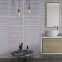 Modern bathroom interior with minimalist design, featuring gray textured wall tiles, industrial-inspired hanging pendant lights, frameless rectangular mirror, floating wooden vanity with white vessel sink, and a round glass side table with small potted plants and toiletries.