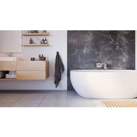 Modern bathroom interior with freestanding white bathtub, wooden vanity cabinet, marble walls, floating shelves with toiletries, grey towel, and tiled flooring.