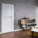 Modern minimalist room with white door, gray textured wall, wooden floor, contemporary sideboard with storage compartments, and yellow accent ottoman.