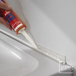 Applying silicone sealant from a caulk gun to seal the edge between wall and bathtub for a waterproof bathroom finish