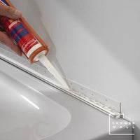 Applying silicone sealant from a caulk gun to seal the edge between wall and bathtub for a waterproof bathroom finish