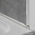 Close-up of caulk applied to seal the edge between a bathtub and gray shower wall tiles with a chrome trim finishing piece and Showerwall branding