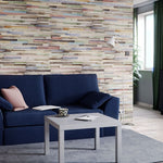 Modern living room interior with blue sofa, colorful geometric wallpaper design, minimalist coffee table, floor lamp, decorative cushions, houseplant, and magazine.