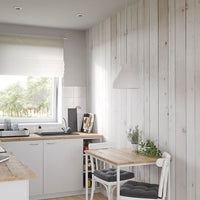 Modern Scandinavian kitchen interior design with white cabinets, wooden countertops, rustic white paneled walls, and a cozy dining area with natural light filtering through a large window.