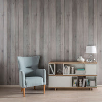 Modern minimalist living room with pastel blue wingback chair, wooden sideboard with books and lamp, and gray wooden plank wall.