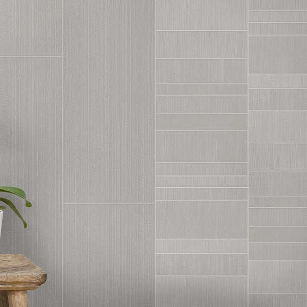 Modern gray tile wall with different textures, wooden stool, and green houseplant on light gray flooring