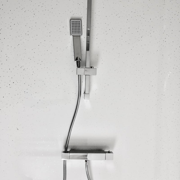 Modern bathroom with wall-mounted showerhead and faucet, chrome finish, on a white tiled wall with water droplets
