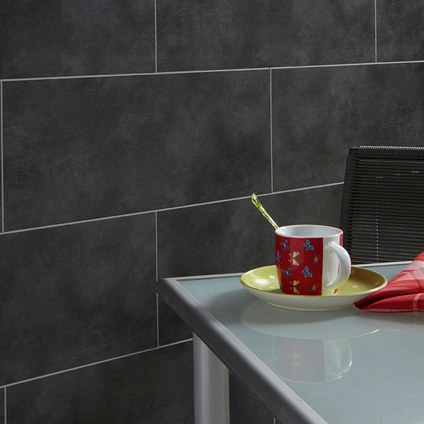 Modern kitchen with grey tiles, glass table, decorative red flower cup on yellow saucer with teaspoon, and red napkin next to black chair
