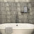 Modern bathroom with white freestanding bathtub, gray tiled wall, wall-mounted faucet, towel, and decorative art with inspirational quotes