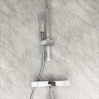 Modern bathroom with stainless steel handheld showerhead and mixer tap mounted on a marble wall