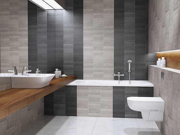 Modern bathroom interior with gray and beige tiles, wooden countertop with white vessel sinks, wall-mounted faucet, built-in bathtub, skylight, white toilet, and minimalist decor.