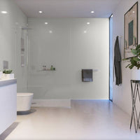 Modern bathroom interior design with glass shower enclosure, white toilet, vanity sink, large mirror, recessed ceiling lights, grey towels, and decorative plant.