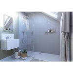 Modern bathroom interior with glass walk-in shower, hexagonal white tiles, floating vanity sink, wall mirror, skylight, gray shower curtain, and decorative plants in wicker baskets.