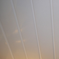 Abstract angled view of off-white vertical lines possibly representing curtains or architectural details with subtle warm light reflection in the background indicating sunrise or sunset.